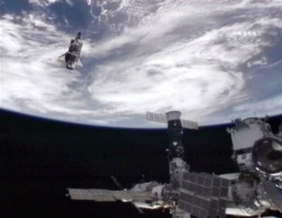 Space shuttle Atlantis, top left, moves away from the International Space Station after undocking, Sunday, May 23, 2010.